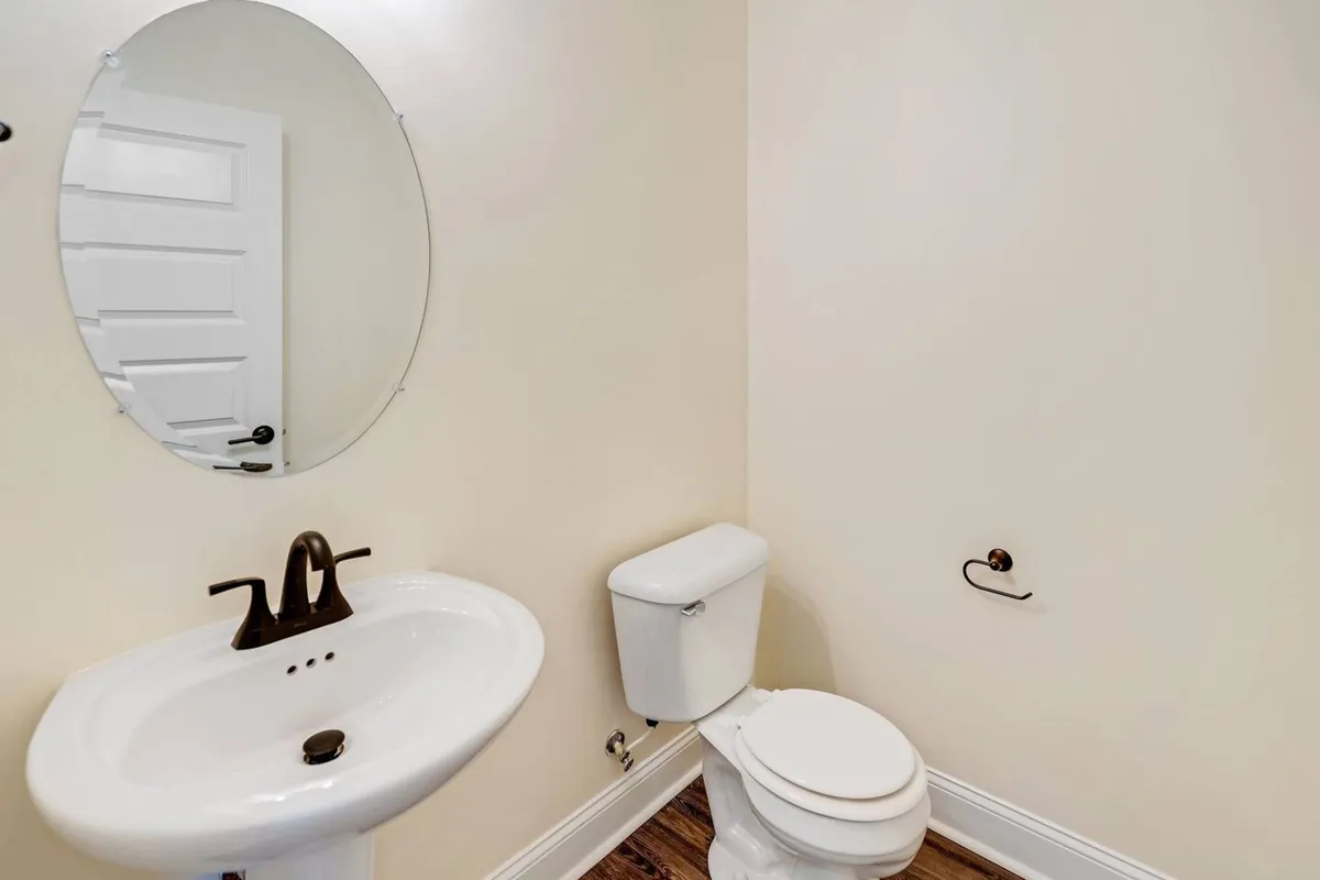 A compact bathroom featuring a sink, mirror, and toilet. The mood is calm and serene, perfect for a quick freshen-up or a moment of quiet.