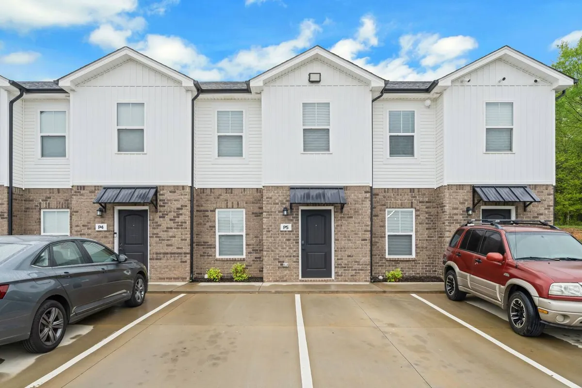 A friendly neighborhood exterior with townhouses, parked cars, and lush landscaping. The image captures a sense of community and ease, suggesting a supportive and safe environment close to local amenities.