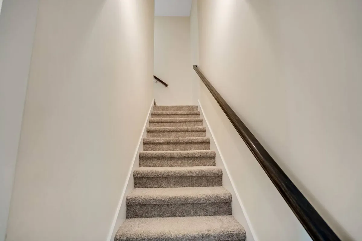 This image features an inviting staircase with a sturdy handrail and warmly painted walls, creating a welcoming pathway between the home's levels. The scene hints at the comfort and space available within the property, suggesting ease of movement for family members throughout the home.