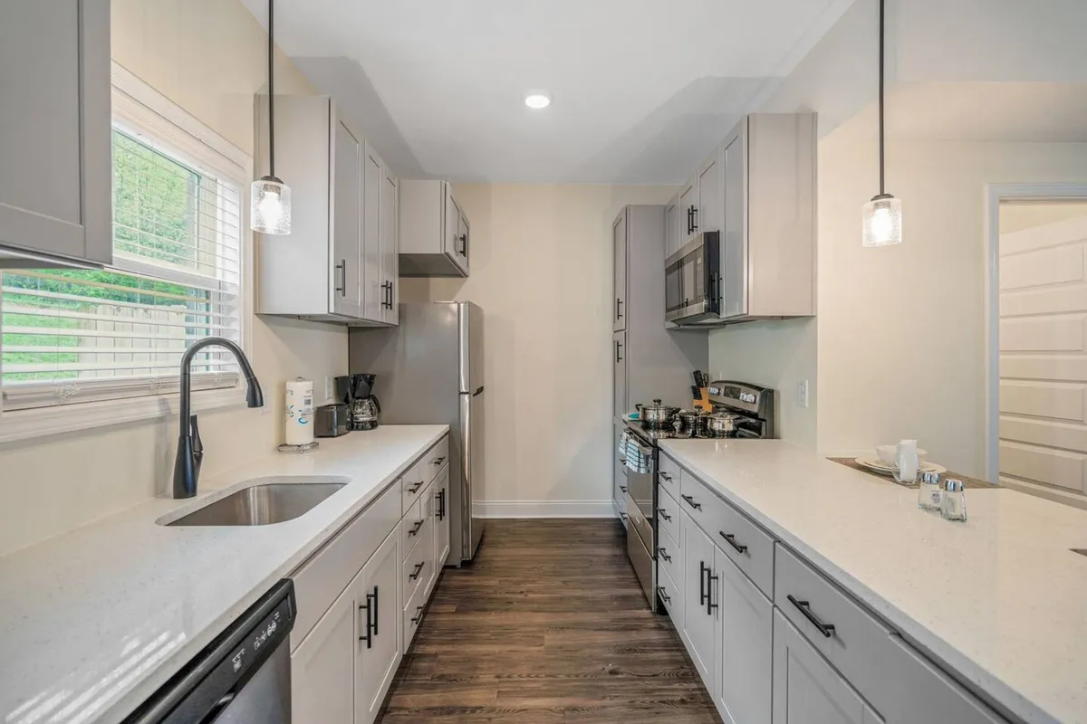 A bright, modern kitchen featuring sleek cabinetry, high-end stainless steel appliances, and spacious countertops. A window above the sink lets in natural light, while the open layout connects seamlessly to the living and dining areas. The kitchen exudes a contemporary, welcoming vibe perfect for meal preparation and socializing.