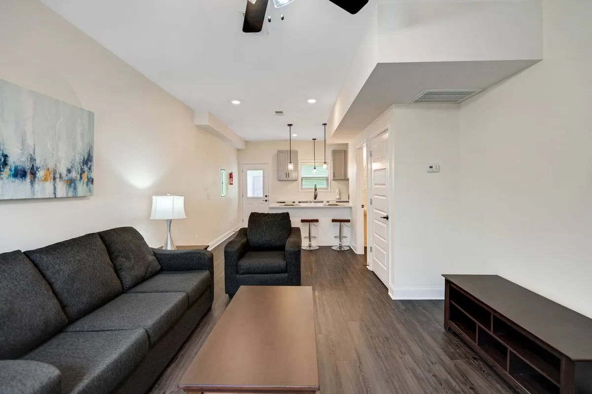 A bright, welcoming space with a plush sofa, coffee table, and a kitchen counter in view. The space is designed for comfort and socializing, with modern touches and a relaxed atmosphere that encourages both gatherings and quiet moments.