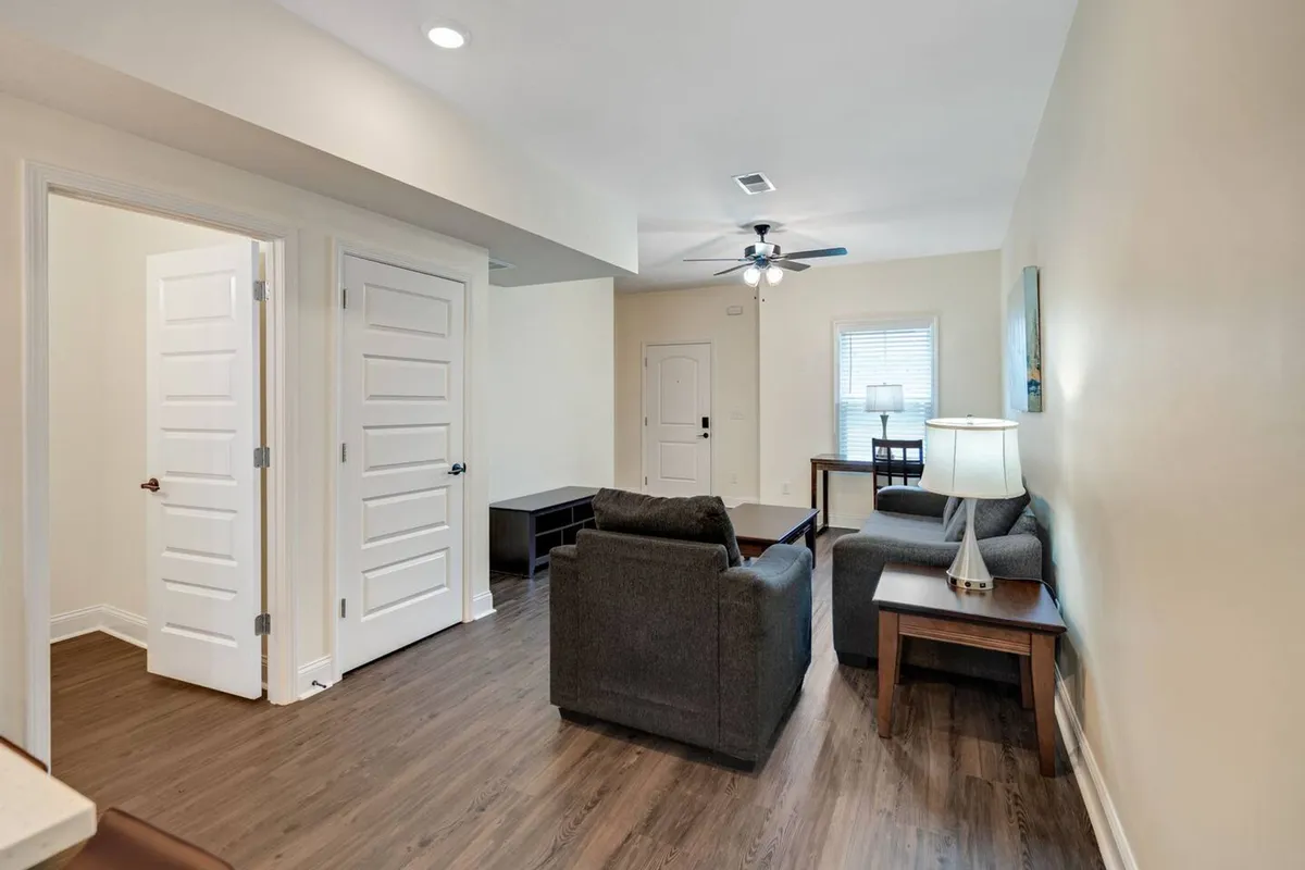 A cozy living room featuring a plush sofa set, a wooden table, and a table lamp. The arrangement is inviting, with soft lighting and comfortable furnishings that exude a sense of homeliness and readiness for relaxation or socializing.